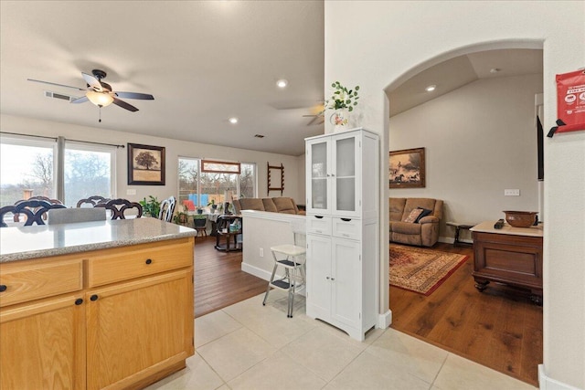 kitchen featuring lofted ceiling, light tile patterned floors, ceiling fan, and light brown cabinets