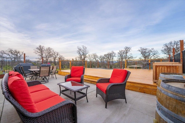 patio terrace at dusk featuring a wooden deck and outdoor lounge area