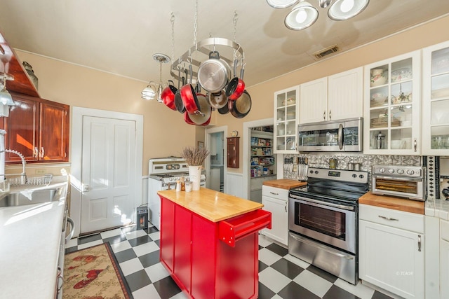 kitchen featuring a kitchen island, wood counters, sink, white cabinets, and stainless steel appliances