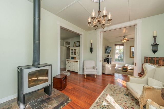 living room with ceiling fan, a wood stove, and dark hardwood / wood-style flooring