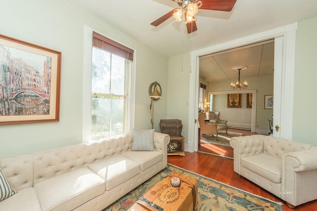 living room with dark wood-type flooring, plenty of natural light, and ceiling fan with notable chandelier