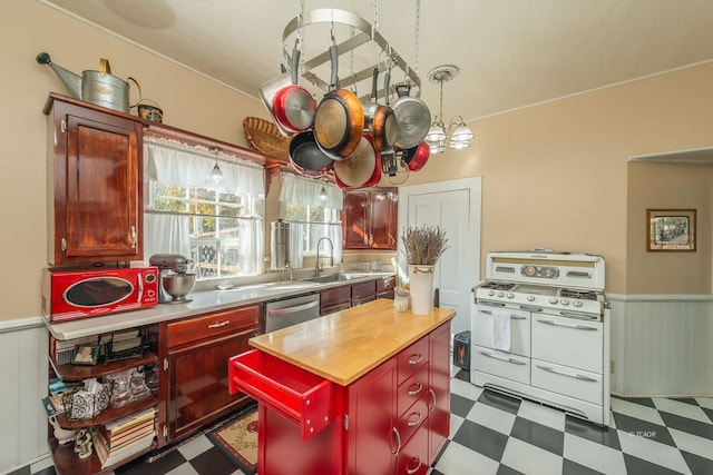 kitchen with sink, wooden counters, a kitchen island, stainless steel dishwasher, and range with two ovens