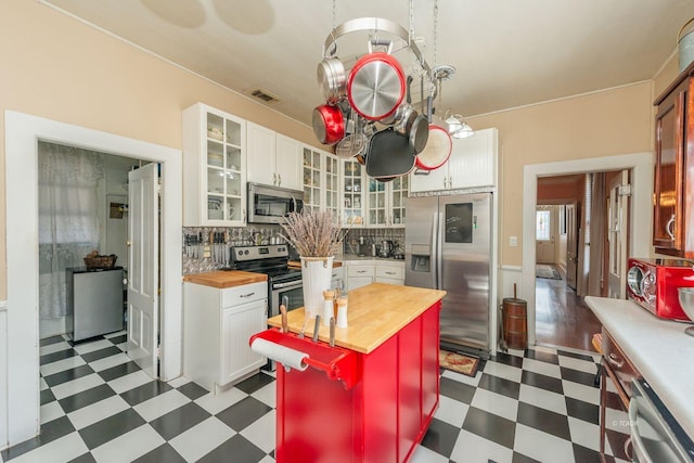 kitchen featuring stainless steel appliances, a center island, white cabinets, wood counters, and decorative backsplash