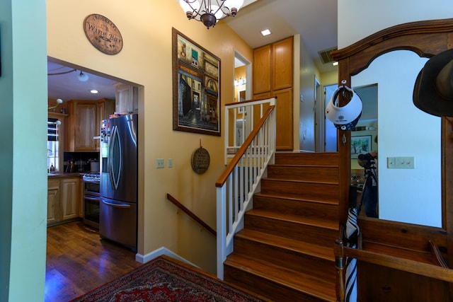 staircase featuring hardwood / wood-style floors and a notable chandelier