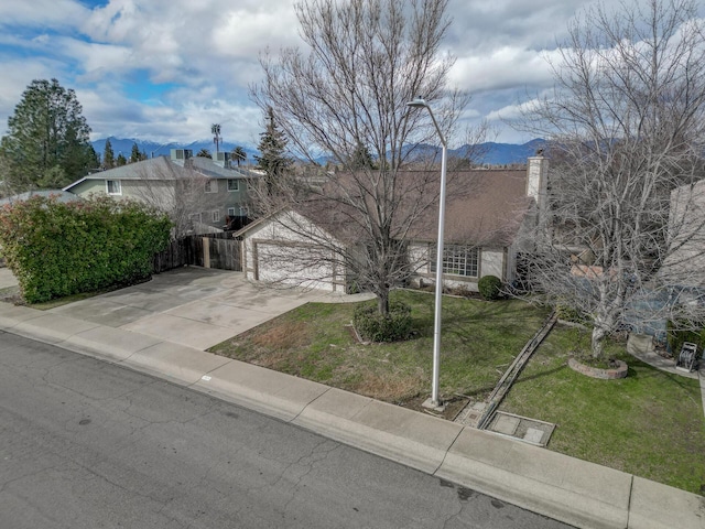 view of front of property with a garage, a mountain view, and a front lawn