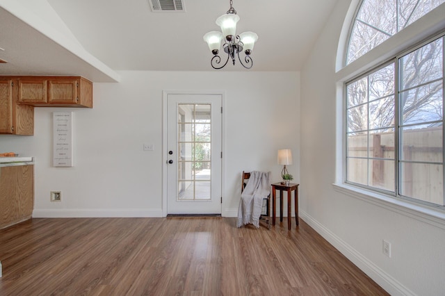 doorway featuring vaulted ceiling, hardwood / wood-style floors, and a notable chandelier