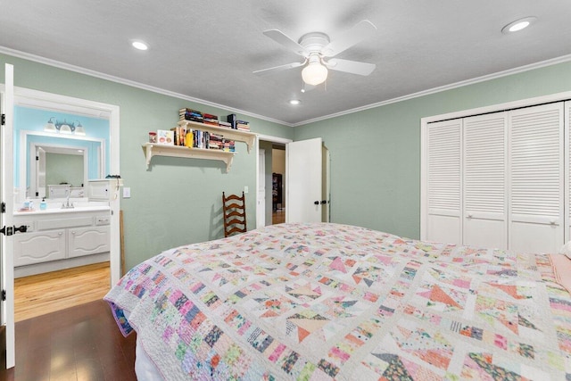 bedroom featuring sink, hardwood / wood-style floors, crown molding, and a closet