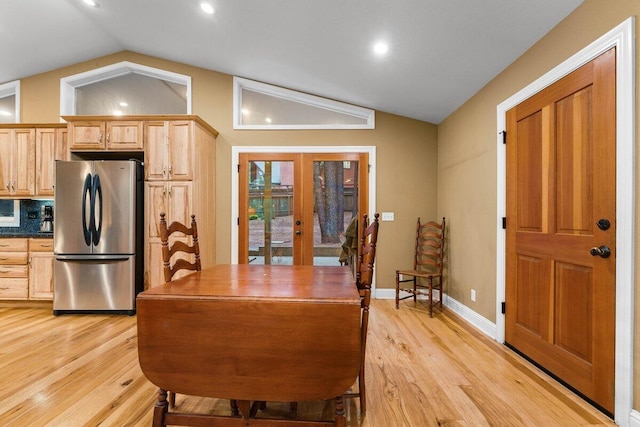 kitchen featuring stainless steel fridge, light brown cabinetry, vaulted ceiling, and light wood-type flooring