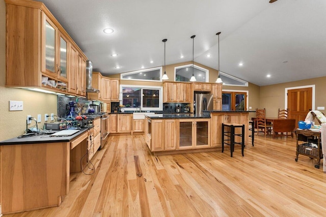 kitchen featuring a kitchen island, a breakfast bar, hanging light fixtures, stainless steel appliances, and light hardwood / wood-style flooring