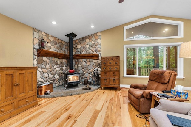 living room featuring wood-type flooring, vaulted ceiling, and a wood stove