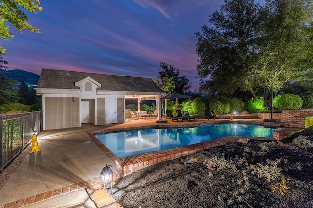 pool at dusk with an outbuilding and a patio area