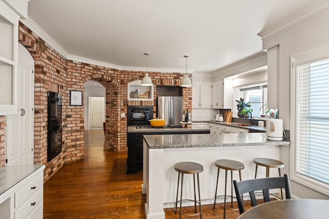 kitchen with dark hardwood / wood-style floors, decorative light fixtures, white cabinetry, black appliances, and light stone countertops