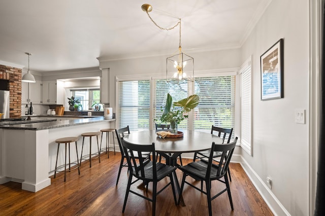 dining room featuring dark wood-type flooring, sink, crown molding, and an inviting chandelier