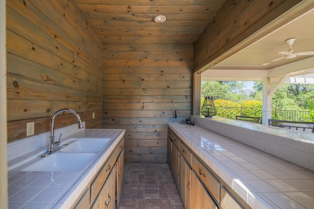 interior space featuring sink, wooden ceiling, ceiling fan, and wood walls