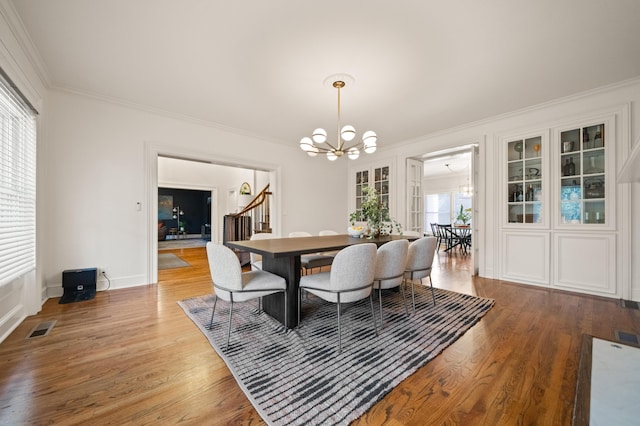 dining area with wood-type flooring, crown molding, and a chandelier