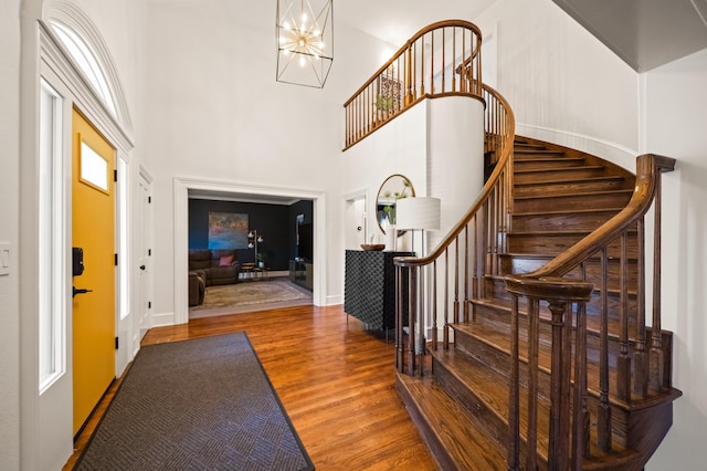 entrance foyer with hardwood / wood-style floors, a notable chandelier, and a towering ceiling