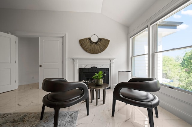 sitting room featuring vaulted ceiling and a fireplace