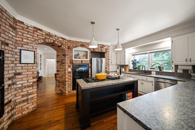 kitchen with a kitchen island, appliances with stainless steel finishes, decorative light fixtures, white cabinetry, and sink