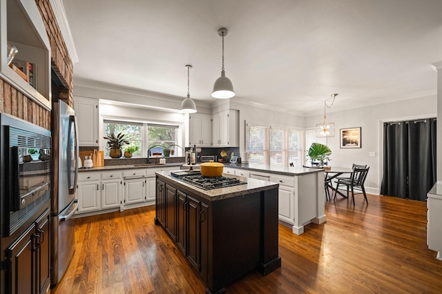 kitchen featuring appliances with stainless steel finishes, white cabinetry, plenty of natural light, a center island, and decorative light fixtures