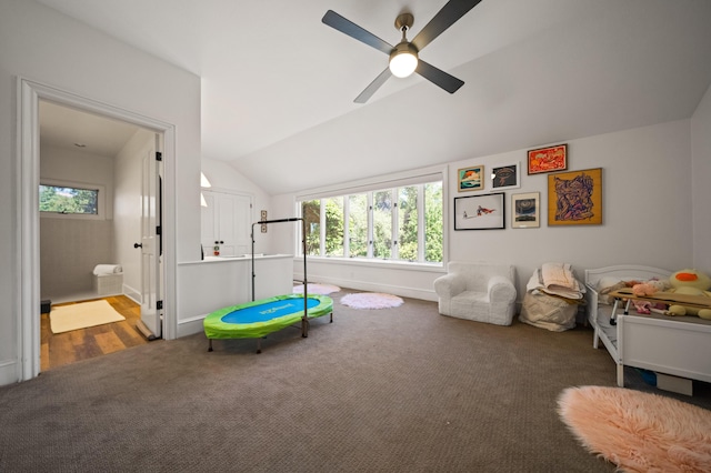 playroom with vaulted ceiling, ceiling fan, and dark colored carpet