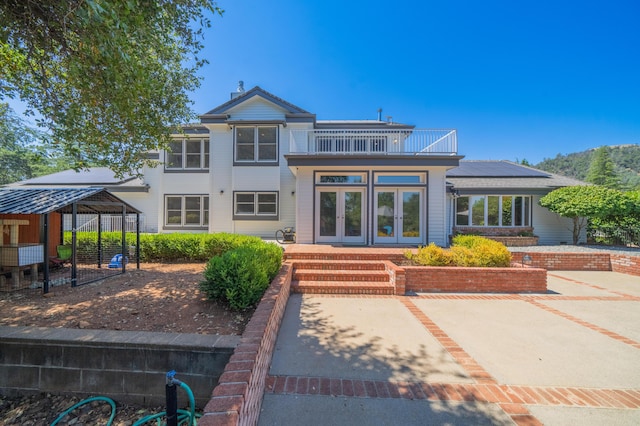 back of property with a patio, french doors, and a balcony