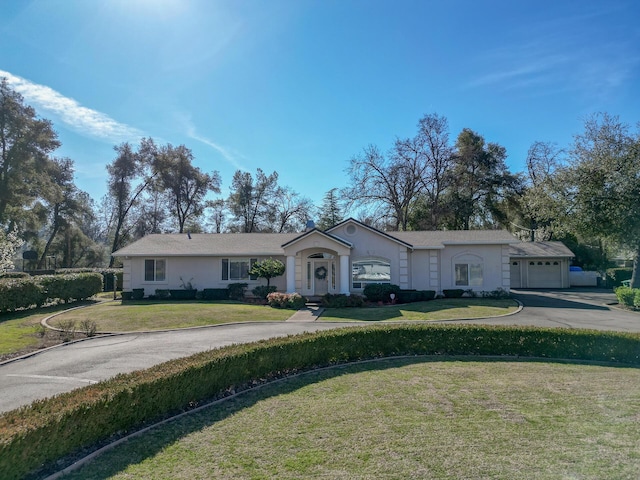 ranch-style house with a garage, driveway, a front lawn, and stucco siding