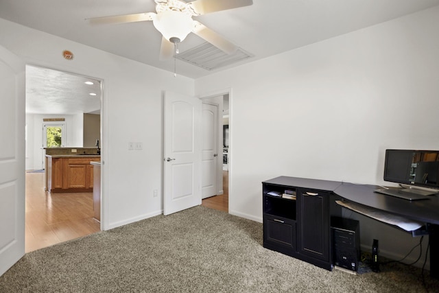 office area with light colored carpet, baseboards, ceiling fan, and a sink