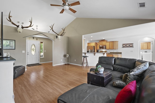 living room featuring visible vents, light wood-style floors, arched walkways, high vaulted ceiling, and a ceiling fan