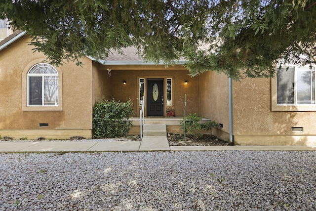 view of exterior entry with crawl space, a porch, and stucco siding