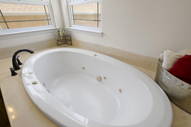 full bathroom featuring a jetted tub and a textured wall