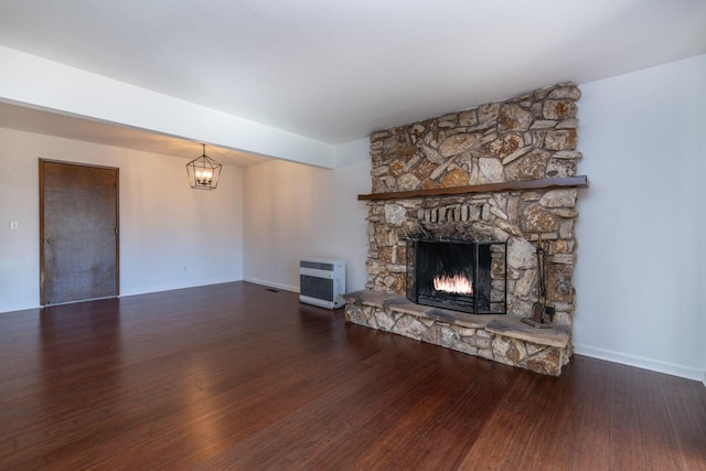 unfurnished living room with an inviting chandelier, wood-type flooring, a fireplace, and heating unit