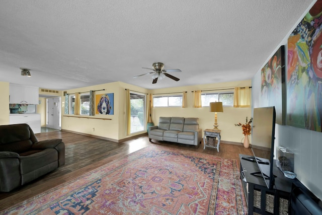 living room featuring ceiling fan, dark hardwood / wood-style flooring, and a textured ceiling