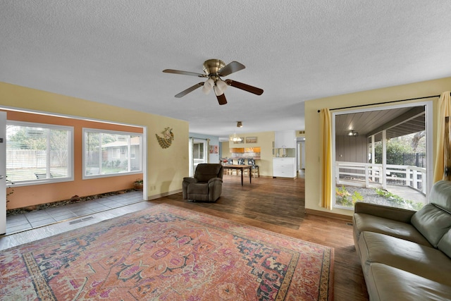 living room featuring ceiling fan, a healthy amount of sunlight, wood-type flooring, and a textured ceiling