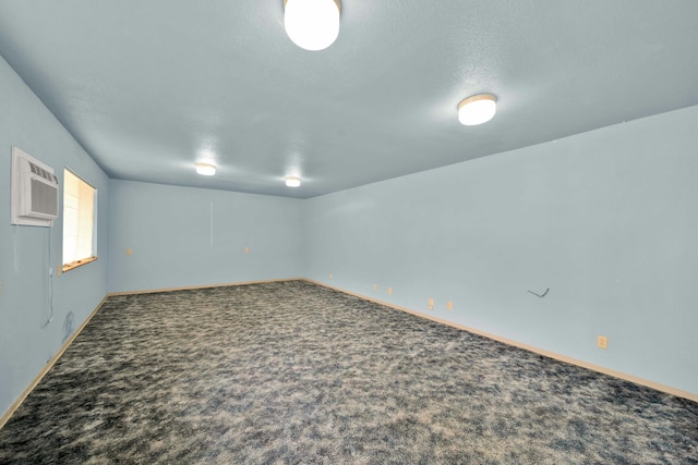 unfurnished room featuring an AC wall unit, carpet flooring, and a textured ceiling