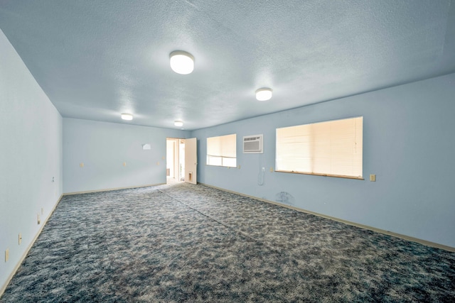 carpeted empty room featuring an AC wall unit and a textured ceiling