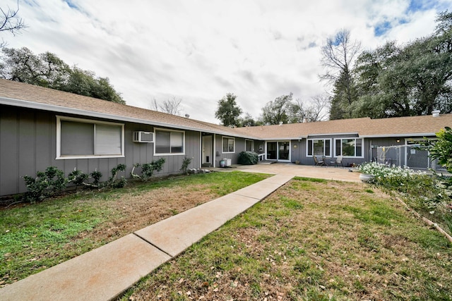 rear view of house featuring a wall unit AC, a yard, and a patio