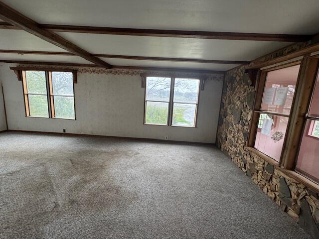 carpeted spare room featuring beam ceiling