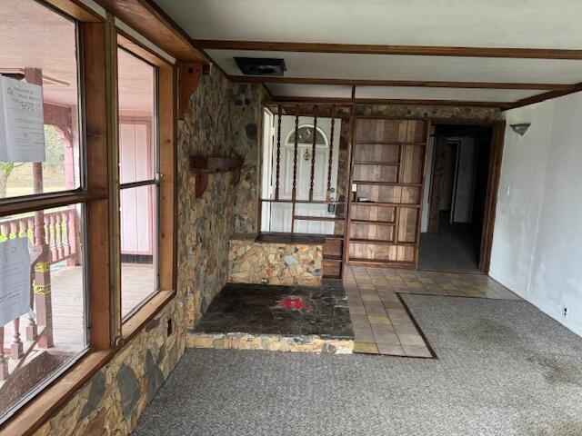 misc room with beam ceiling, a healthy amount of sunlight, and carpet flooring