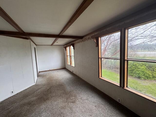 carpeted spare room with beamed ceiling