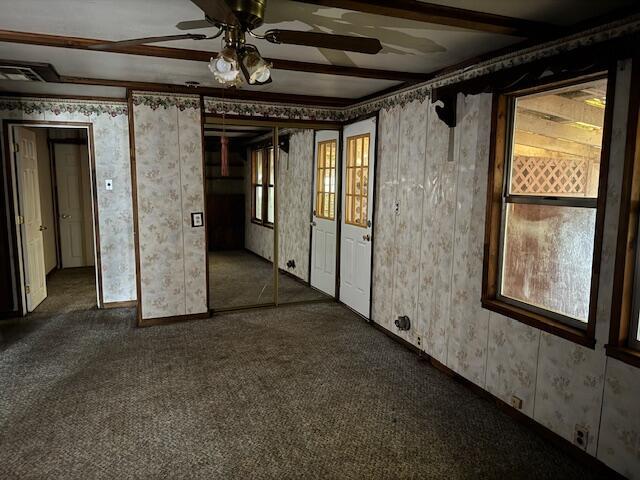 unfurnished room featuring ceiling fan, carpet floors, a wealth of natural light, and beam ceiling