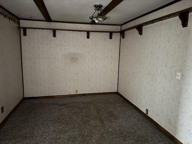 carpeted empty room featuring beamed ceiling