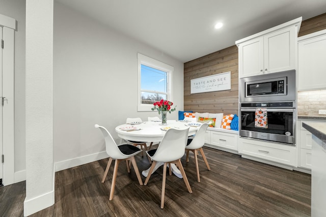 dining area featuring dark wood-type flooring and wood walls