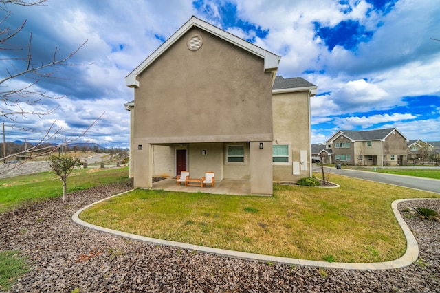 back of property with a yard and a patio