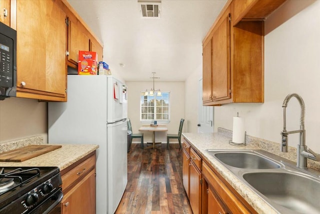 kitchen with dark hardwood / wood-style floors, sink, hanging light fixtures, black appliances, and an inviting chandelier