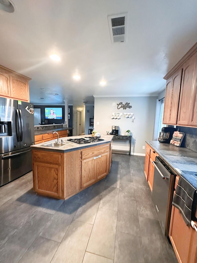 kitchen with sink, crown molding, stainless steel appliances, a center island with sink, and dark tile patterned flooring