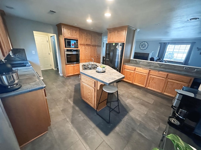 kitchen featuring an island with sink, a kitchen breakfast bar, and black appliances