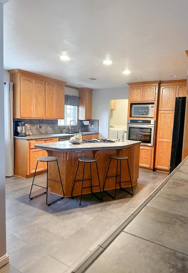 kitchen featuring decorative backsplash, a breakfast bar, a center island, and appliances with stainless steel finishes