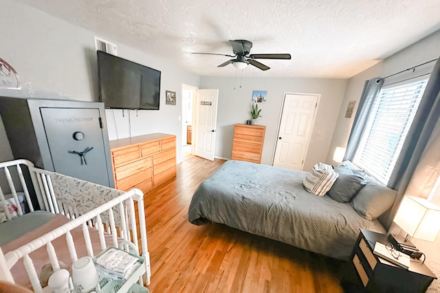 bedroom featuring hardwood / wood-style flooring, ceiling fan, and a textured ceiling