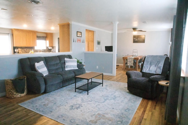 living room with wood-type flooring, decorative columns, and ceiling fan