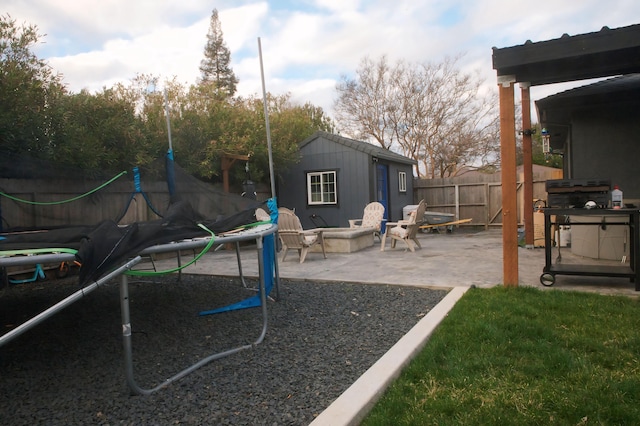 view of play area featuring a patio, a fire pit, and a shed